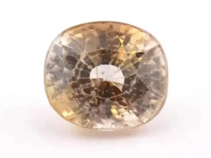 A close-up view of a faceted gems (ZrSiO4) gem showing significant surface abrasion and scratched facet edges.