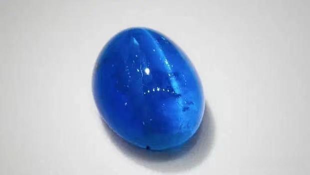 A 12.5ct oval blue apatite cabochon from Brazil showing a sharp, centered cat's eye chatoyancy.