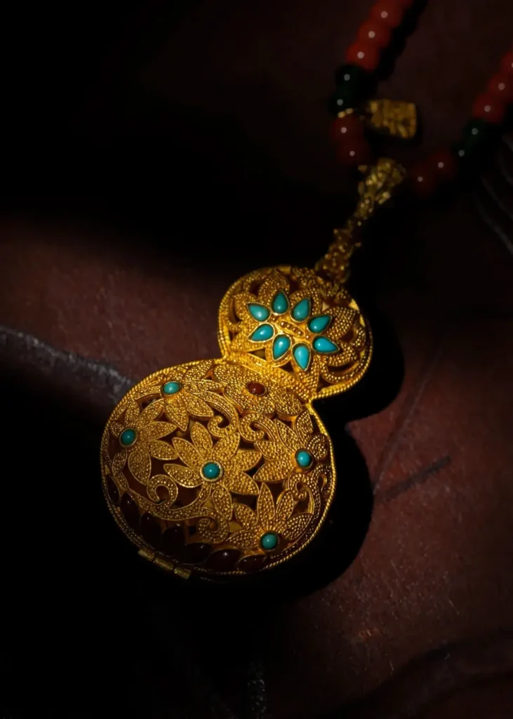 A hollow gold gourd-shaped sachet pendant decorated with intricate filigree.