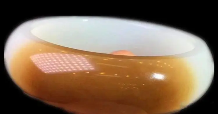 A close-up shot of a high-end Hetian Sugar Jade bangle, showcasing its extreme structural density, rich oily luster, and stable reddish-brown saturation against a minimalist background.