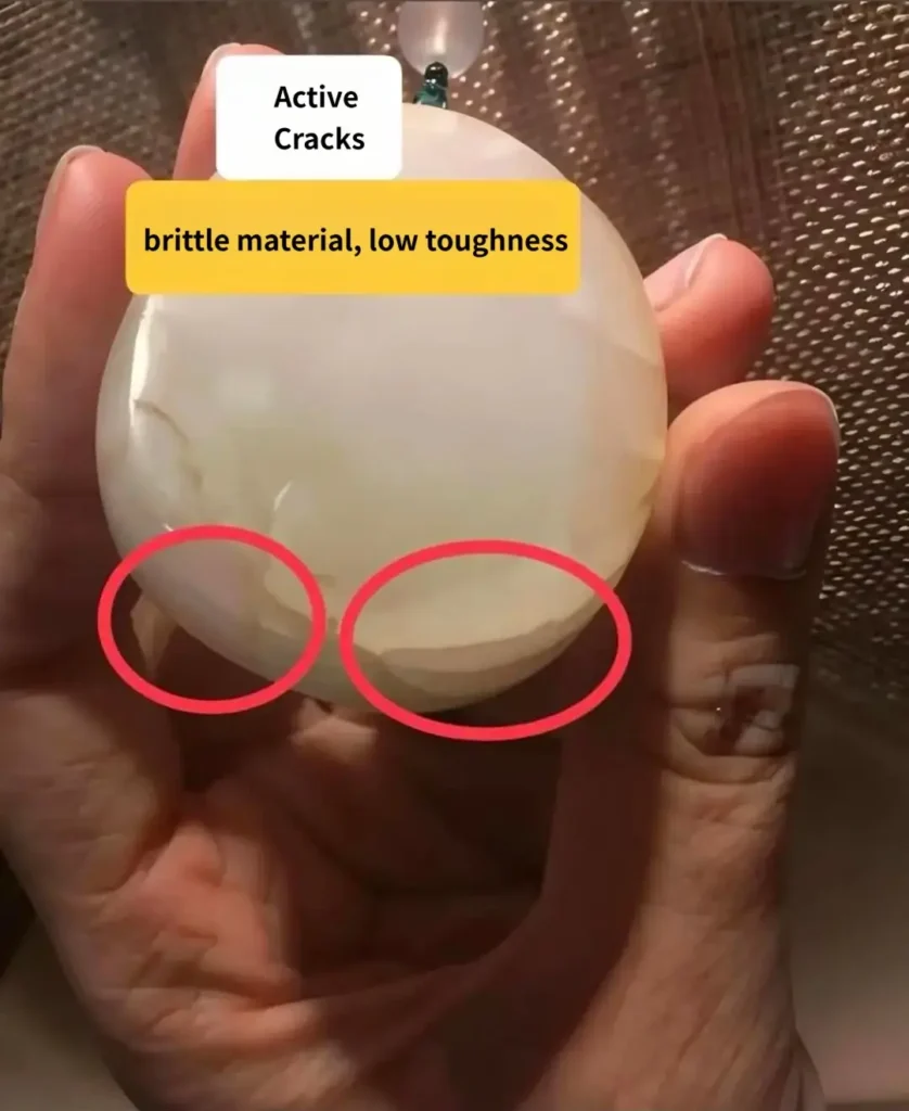 Macro photo of open active cracks on a brittle Hetian jade surface with sharp edges.