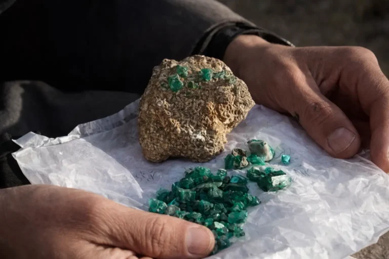 An Afghan gem vendor displaying high-quality rough Panjshir emerald crystals in a traditional market.