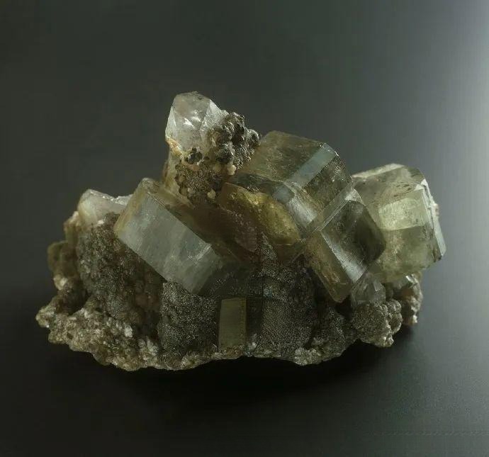 Deep blue apatite crystal surrounded by clusters of round, bubble-like mineral inclusions.