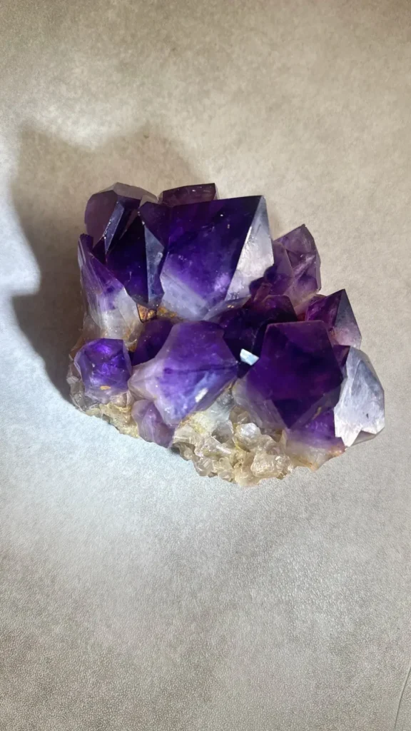 A natural purple amethyst cluster with multiple sharp, translucent hexagonal crystal points.