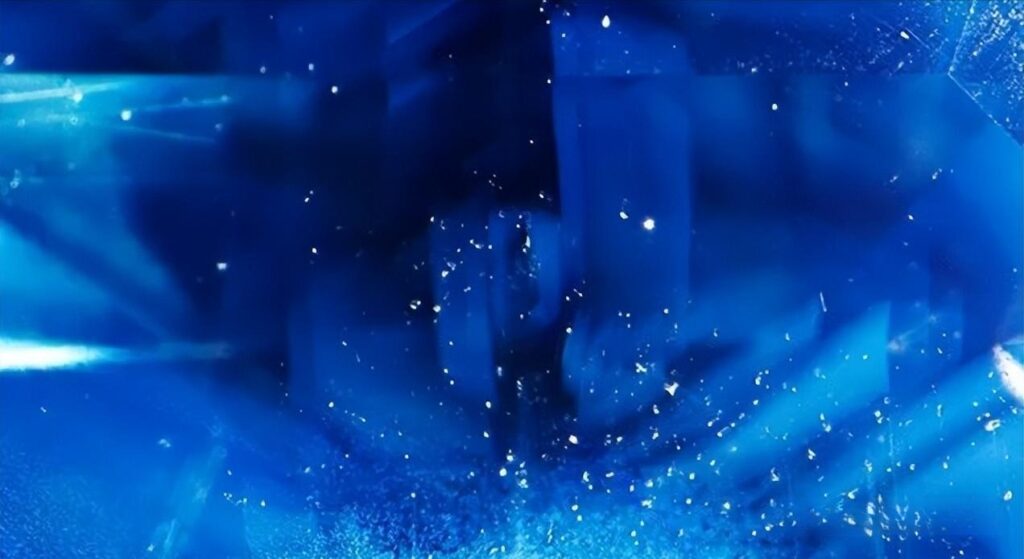 Microscopic Colombian sapphire showing color zoning, angular milky clouds, and distinct twinning lines.