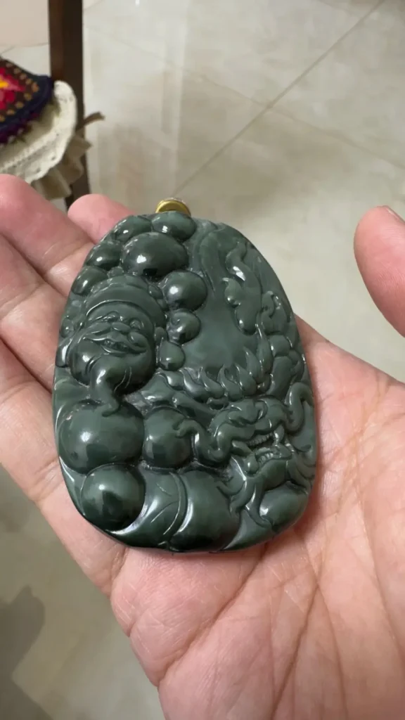 An Afghanistan nephrite pendant with a coarse texture, smoky dark tones, and brownish sugar patches.