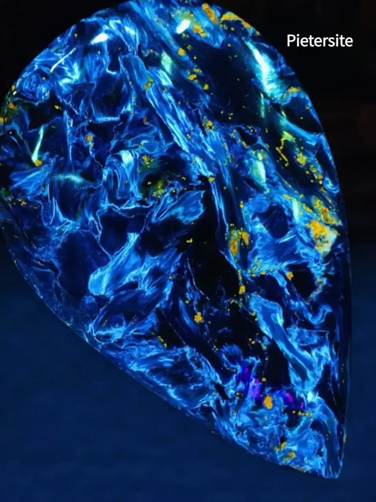 A polished deep blue Pietersite gemstone featuring swirling, chaotic fibrous chatoyant patterns.