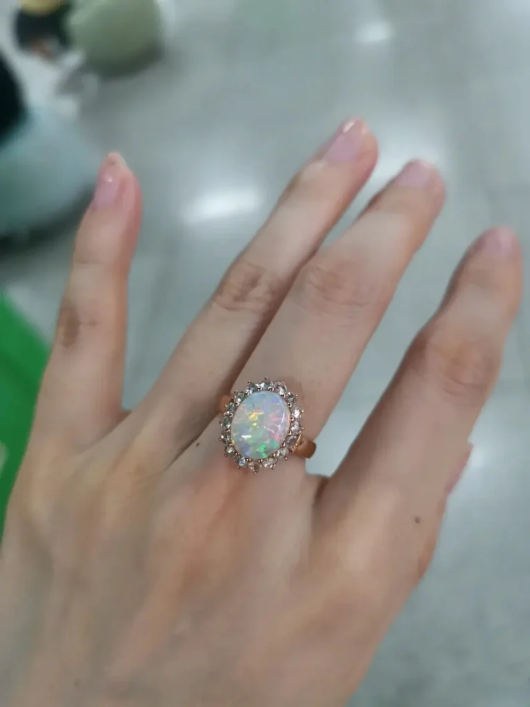 High-end crystal opal ring on a finger showing deep light interaction and elegant spectral colors.