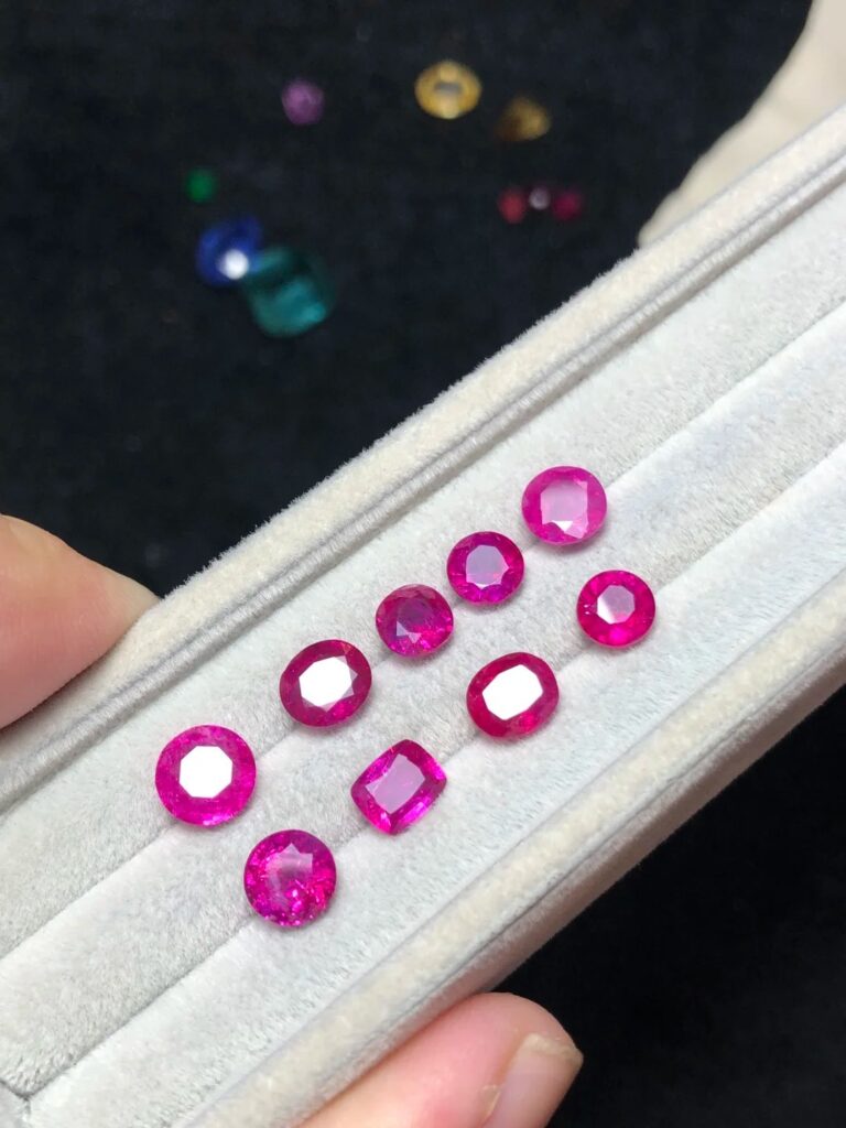 A group of small, faceted Jagdalek rubies showcasing vivid red color and high crystal clarity.