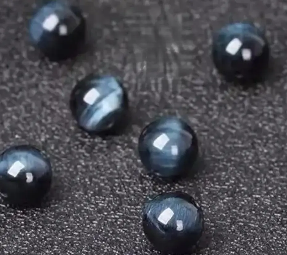 Several deep blue Hawk’s Eye beads showing characteristic fibrous inclusions preserving blue color.