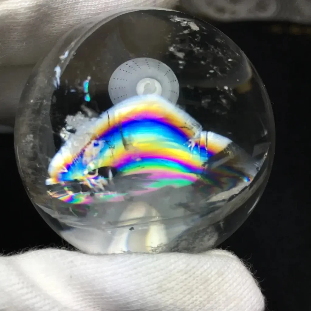 Clear crystal bead showing internal rainbow bands caused by light refraction within healed fractures.
