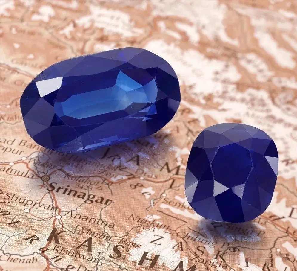 Two large cushion-cut blue Kashmir sapphires weighing 55.19 and 25.97 carats on a neutral background.