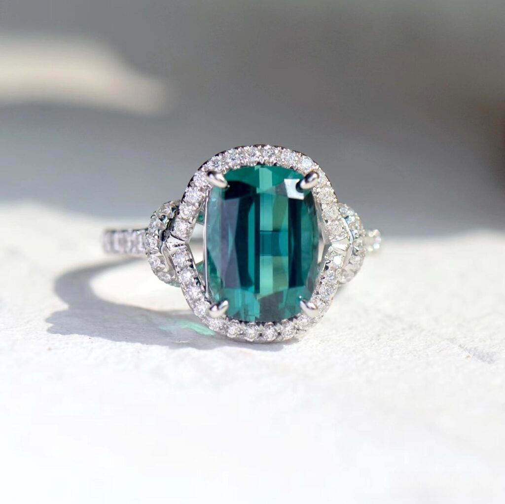 A gemstone ring featuring a bright blue-green Lagoon tourmaline with high brilliance and clarity.