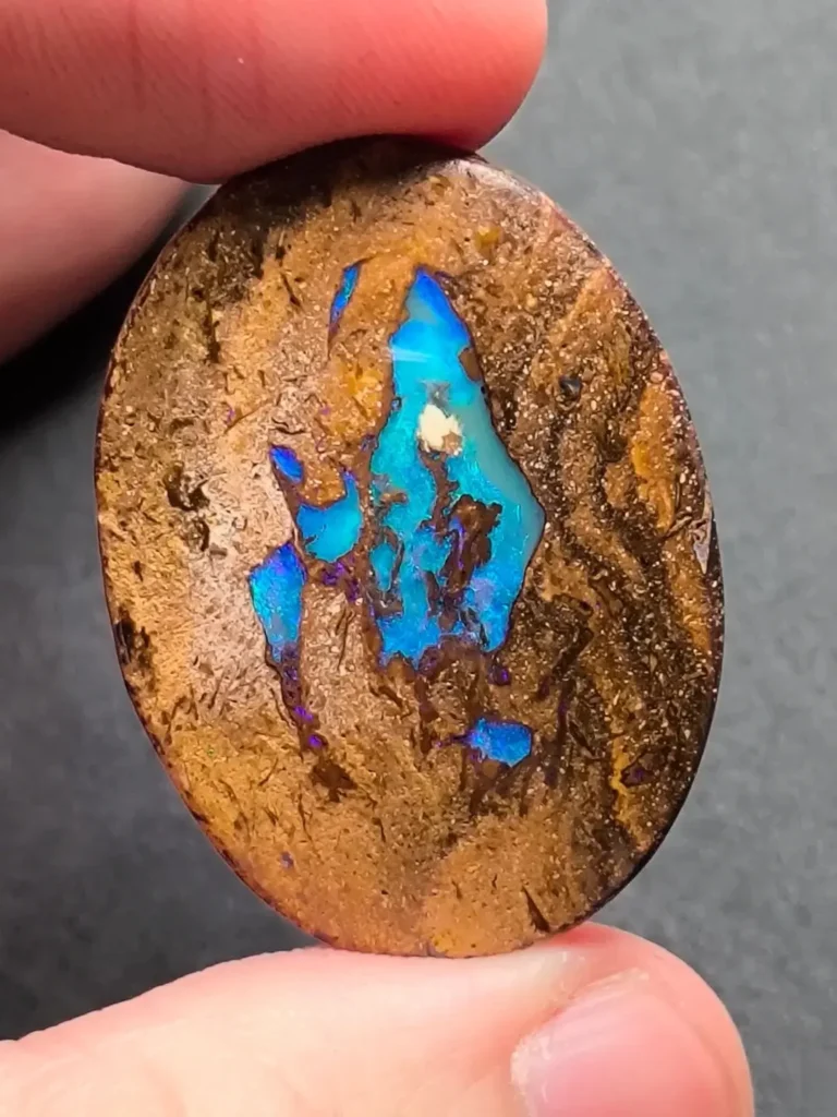Layered boulder opal with wavy blue-green seams sandwiched between dark brown ironstone strata.