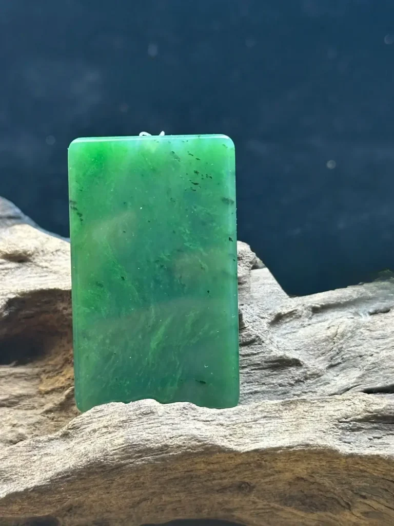A Canadian green hetian jade plaque with uneven color distribution and natural dark green patches.