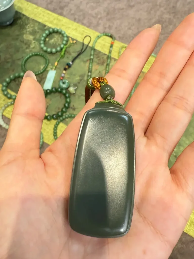 A Qinghai nephrite jade pendant featuring muted olive green tones and a slightly grayish hue.