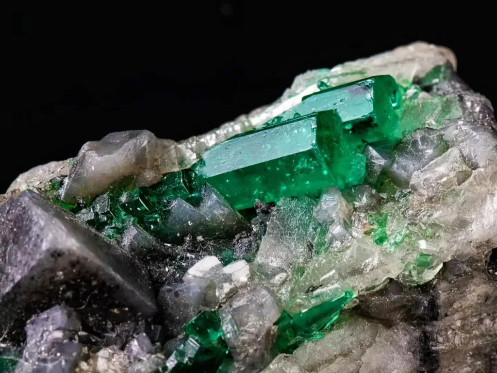 A natural Muzo emerald specimen featuring a short hexagonal crystal embedded in white calcite matrix.