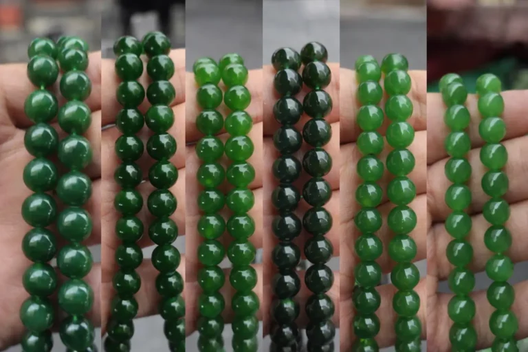 A hand holding different nephrite jade beads from Russia, Canada, Pakistan, and Afghanistan.