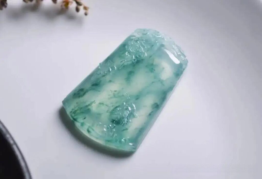 Translucent blue-water jade pendant with fine oily luster and subtle dark blue floating flowers.