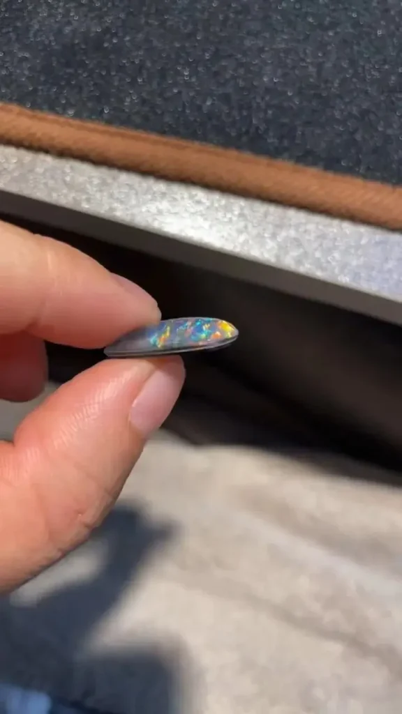 Close-up of an opal doublet showing the distinct straight bonding line between opal and black backing.