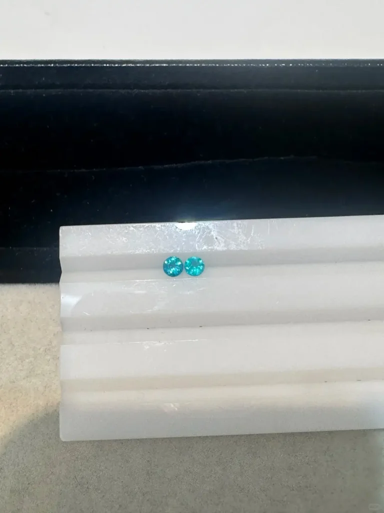 Two gems compared by color and carat: left 0.28ct vivid blue $1,000, right 0.2ct lighter $430.
