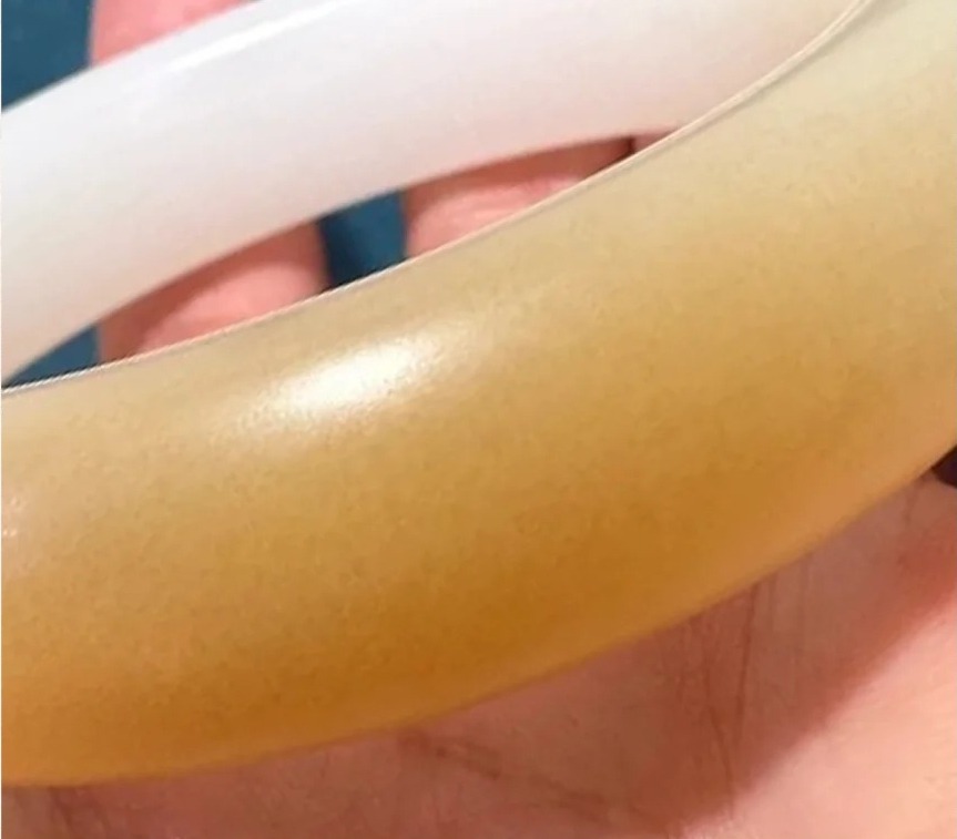 Macro view of the granulated sugar-like internal structure typical of Qinghai nephrite jade under a flashlight.