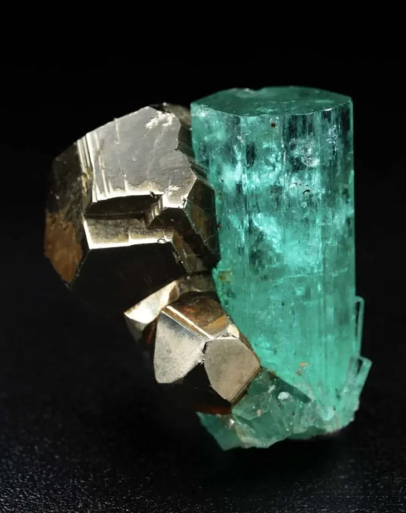 Long isolated Chivor emerald crystal from Colombia with a distinct blue undertone and pyrite inclusions.