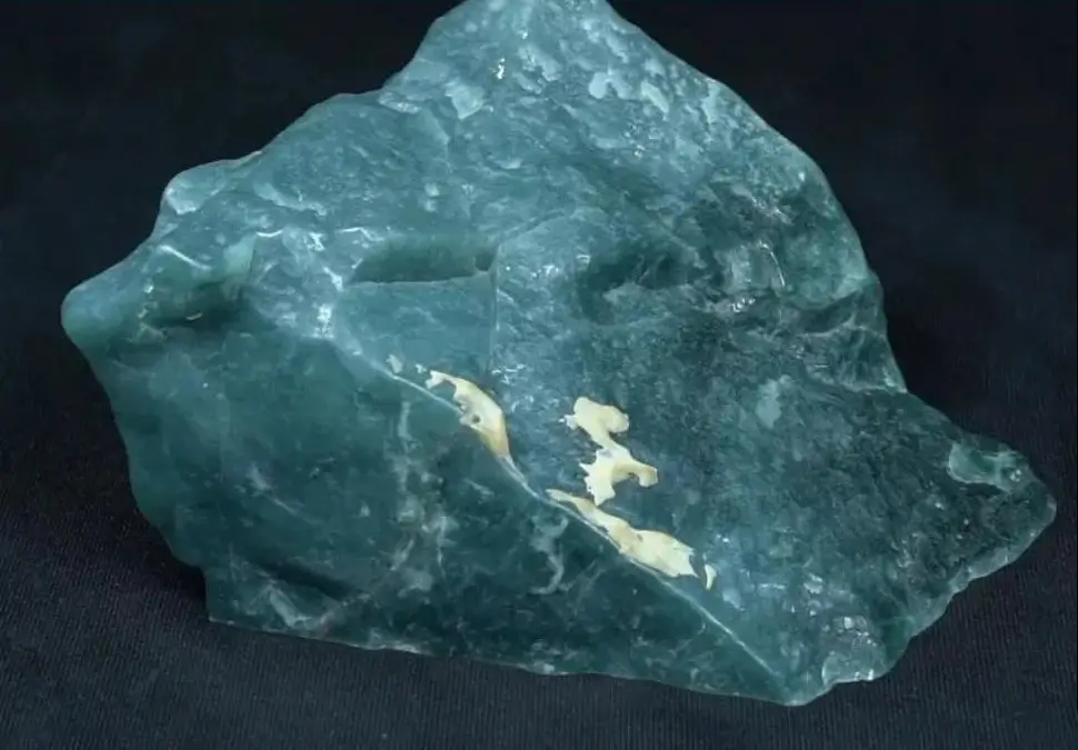 Natural Guatemalan jade raw stone with a grayish-blue translucent core and dark exterior skin.