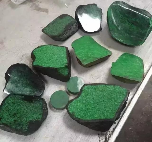 A cluster of vivid green stones with distinct black veins and a slightly waxy luster.