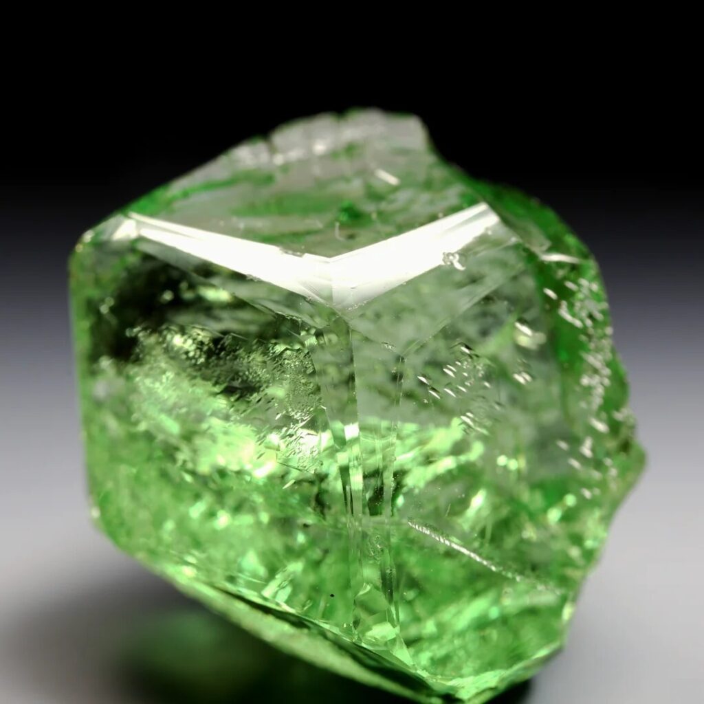 Raw Tanzanian green gem crystal featuring sharp, natural etching marks on its surfaces.