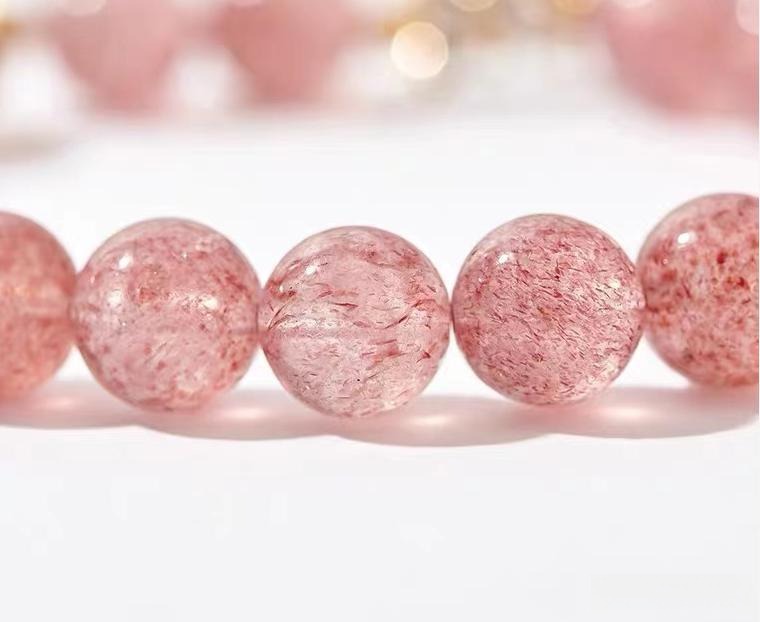 Strawberry crystal bracelet composed of polished quartz beads with red iron oxide inclusions.