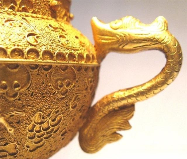A Tang Dynasty gold kettle with intricate filigree and granulation depicting dragon and phoenix motifs.