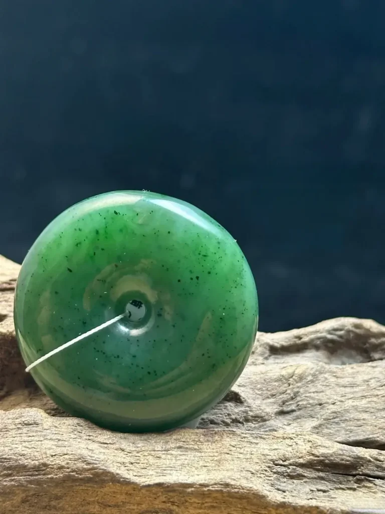 Pakistan nephrite ping an kou with a muted green color, watery translucency, and black spot inclusions.