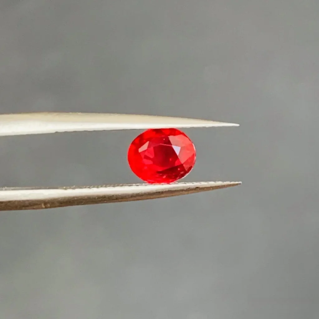 A 1.02ct oval unheated pigeon’s blood ruby alongside its official AIGS gemstone report.