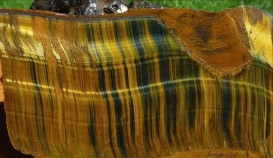 A Zebra Tiger's Eye gemstone with patchy, intermingled bands of golden-brown and blue-grey quartz.