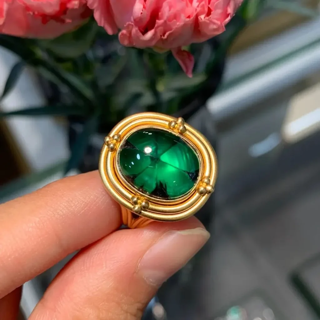 An 18K gold ring featuring a round Colombian Trapiche Emerald with a distinct six-spoke pattern.