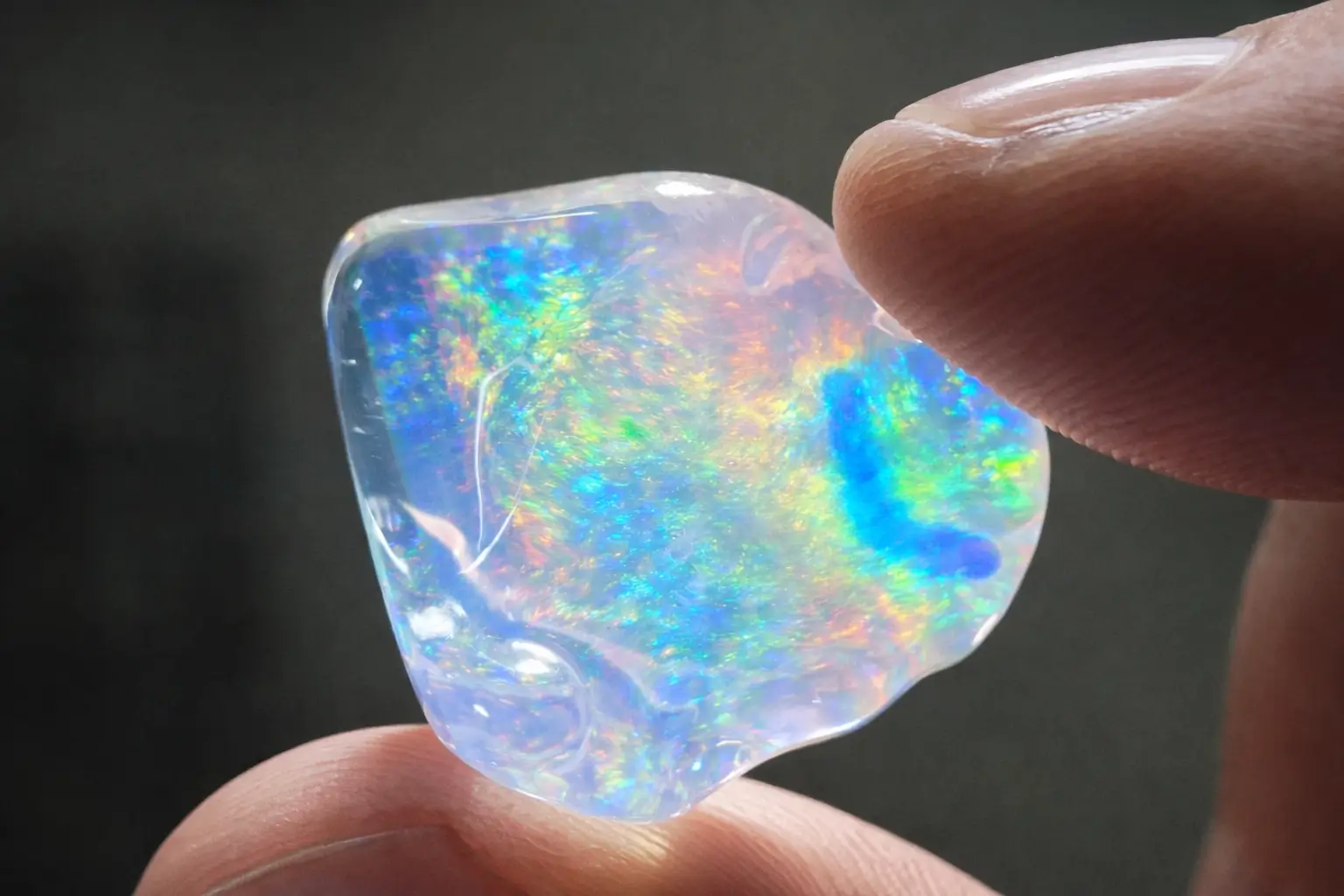 Close-up of an Australian opal gemstone showing intense fiery play-of-color and vibrant rainbow flashes.