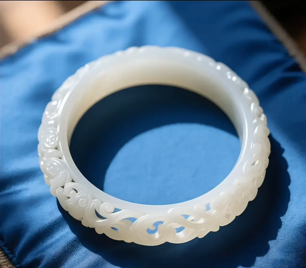 A Jingbai Jade bangle with intricate openwork carvings and a bright, glassy surface.