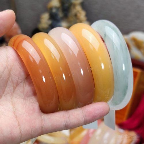 Multiple Jinsi jade bracelets in yellow, red, and white.