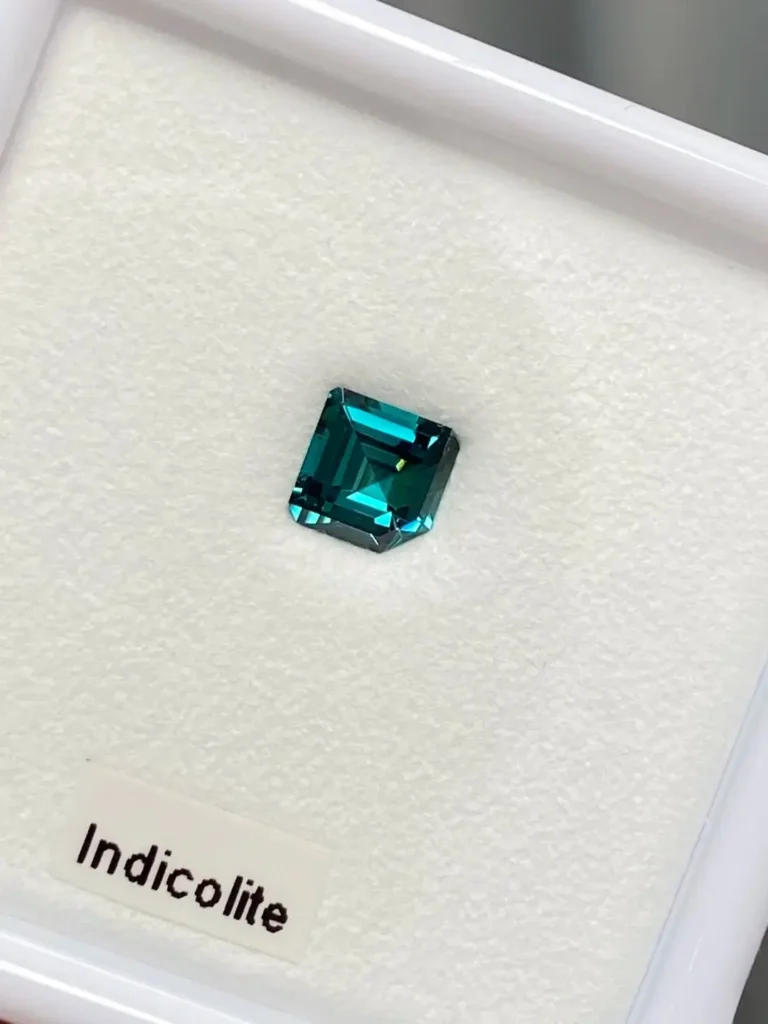 A deep blue cushion-cut Indicolite tourmaline presented in a professional jewelry display box.