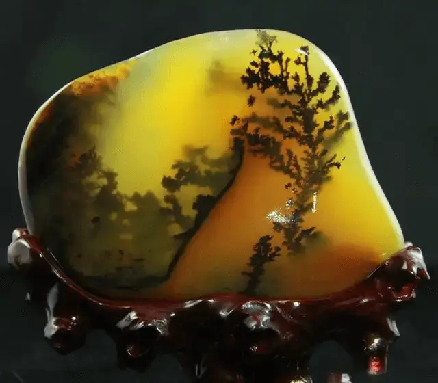 Huanglong Jade ornament featuring natural black dendritic inclusions resembling aquatic plants.