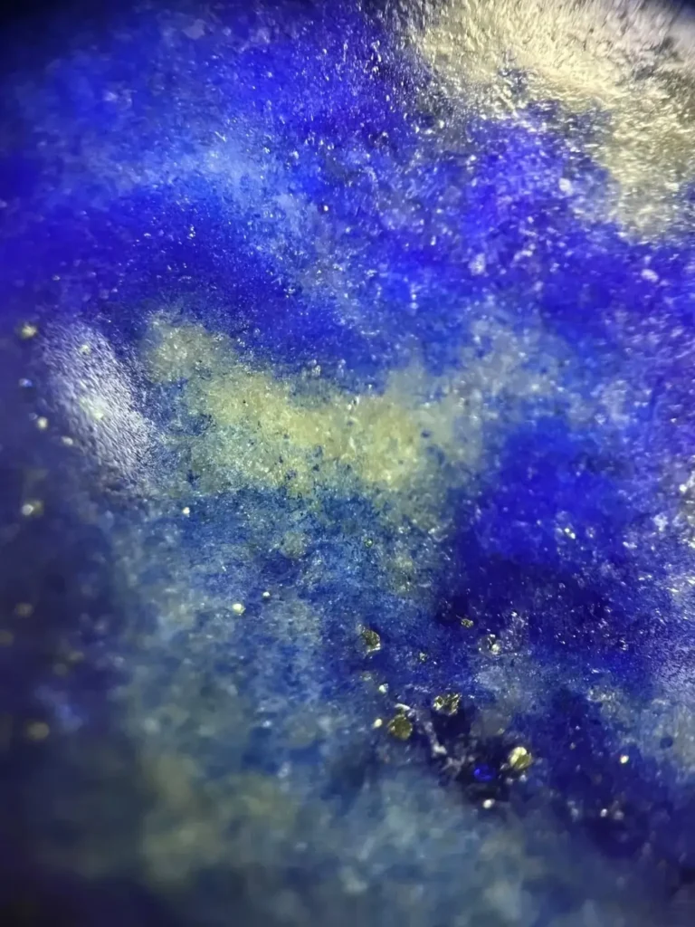 Microscopic view of dyed lapis showing blue-green dye residue concentrated in stone fissures.