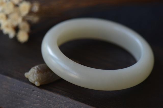 A Grade 1.5 White Hetian Nephrite jade bangle with a visible dusty gray undertone.