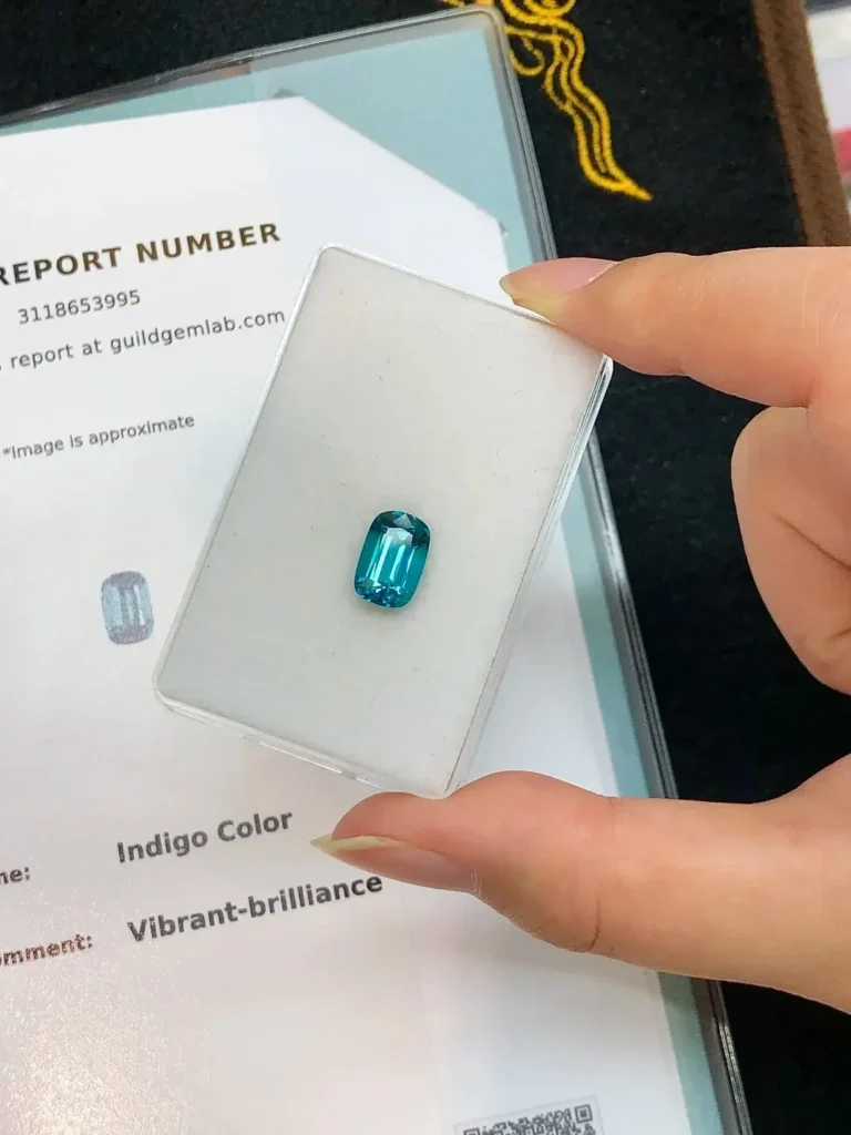 An Afghanistan Indigo tourmaline displayed next to a GUILD laboratory report identifying its color.