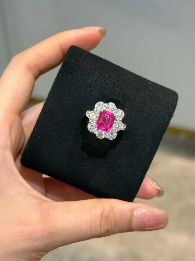 A vibrant hot pink Mahenge spinel ring featuring a classic diamond halo setting.