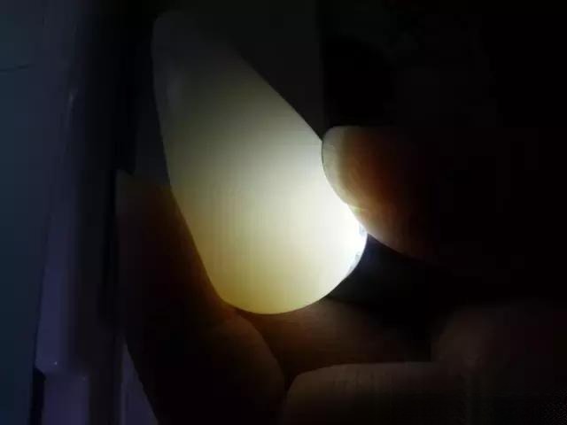 Backlit Hetian Nephrite Jade in darkness showing its characteristic interlocking felt-like weave.