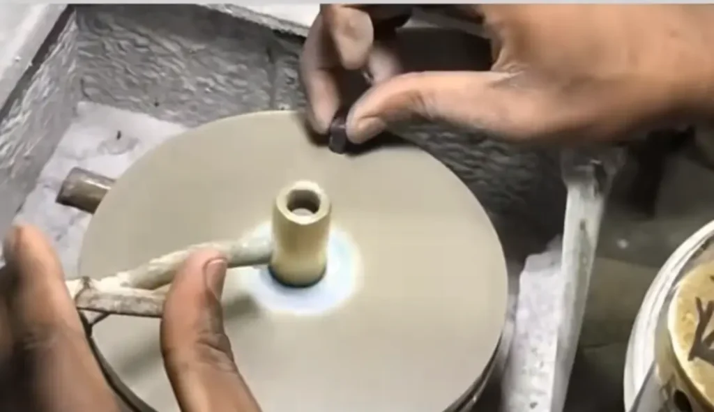 A skilled lapidary precision-cutting a gemstone on a faceting machine in a workshop setting.