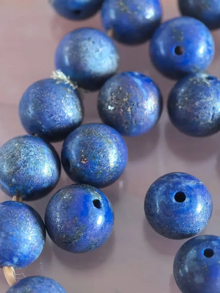 Dull and faded lapis lazuli beads showing surface damage from long-term sweat and chemical exposure.