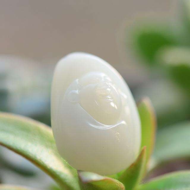 A mature, pure-white seed jade Buddha carving with a waxy, high-density surface and natural shape.