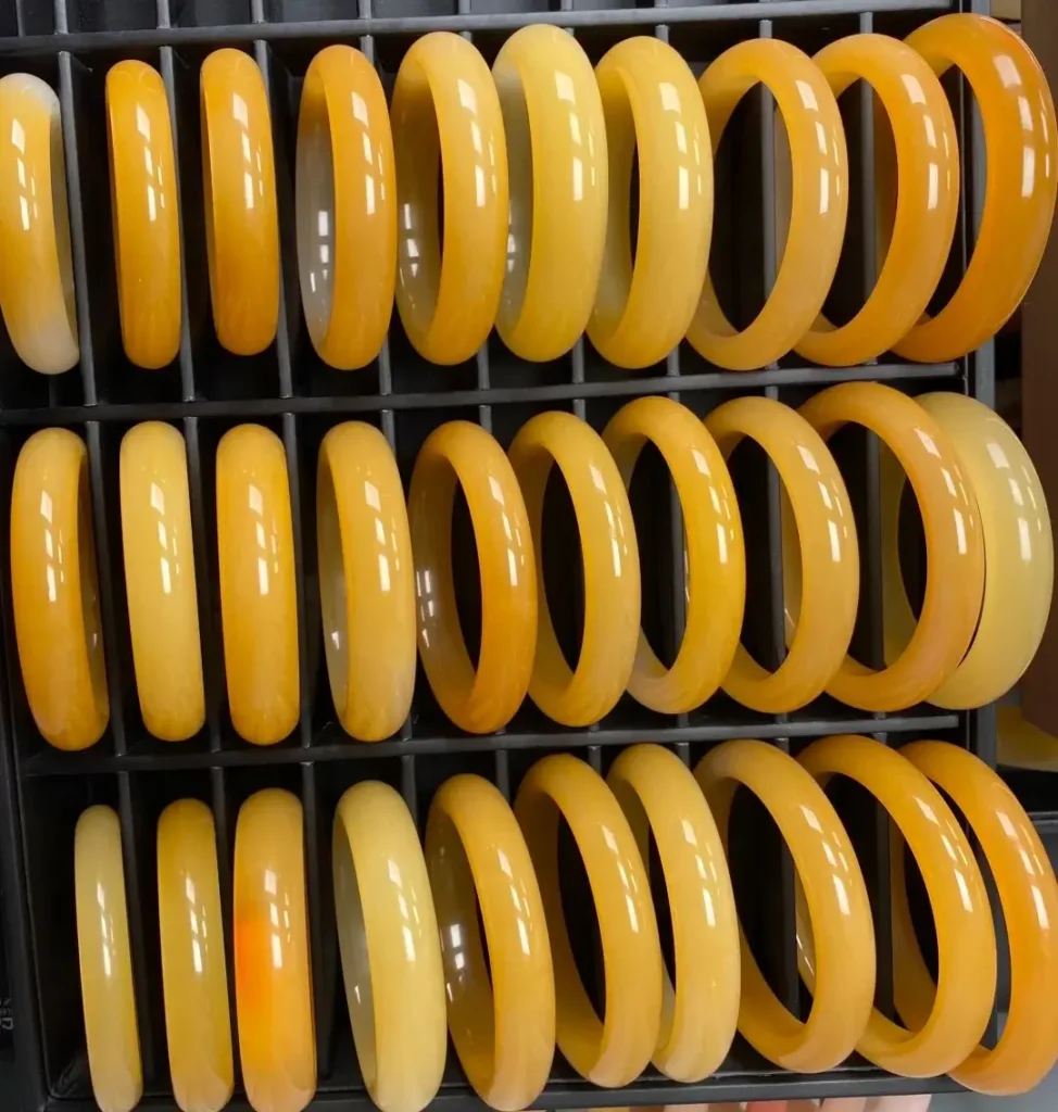 Three rows of mid-priced yellow and orange quartzite bangles displayed in a market setting.